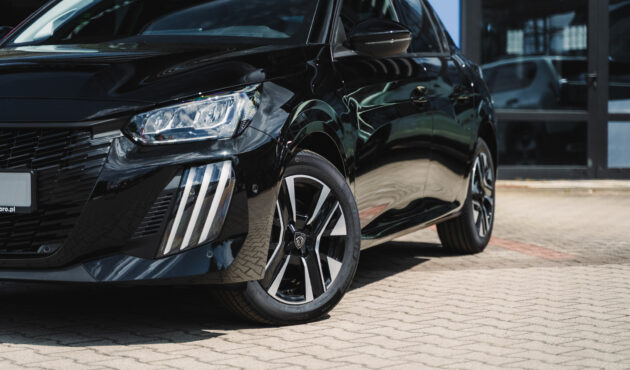 Czarny Peugeot 208 Hybrid przed salonem samochodowym Waro z charakterystycznymi światłami LED w kształcie kłów