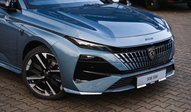 Zbliżony przód niebieskiego Peugeot 308 SW zaparkowanego przed salonem Waro – nowoczesny grill i reflektory LED